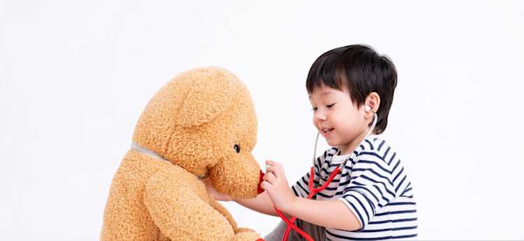 niño con estetoscopio de juguete jugando al doctor con sus oso de peluche