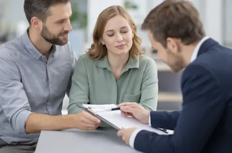 Couple et conseiller immobilier examinant des documents de vente