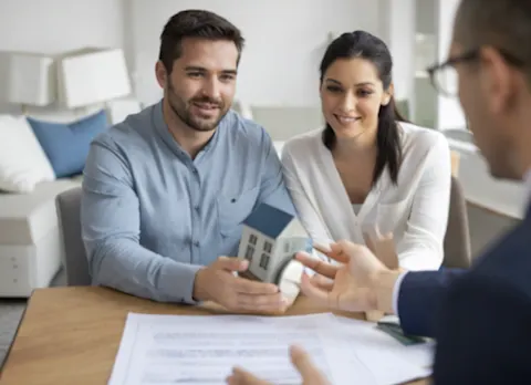 Couple expatrié signant un dossier de crédit immobilier avec un conseiller bancaire