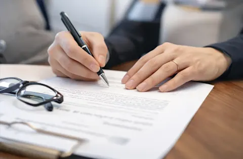 Main en train de signer une lettre de congé pour vente sur un bureau