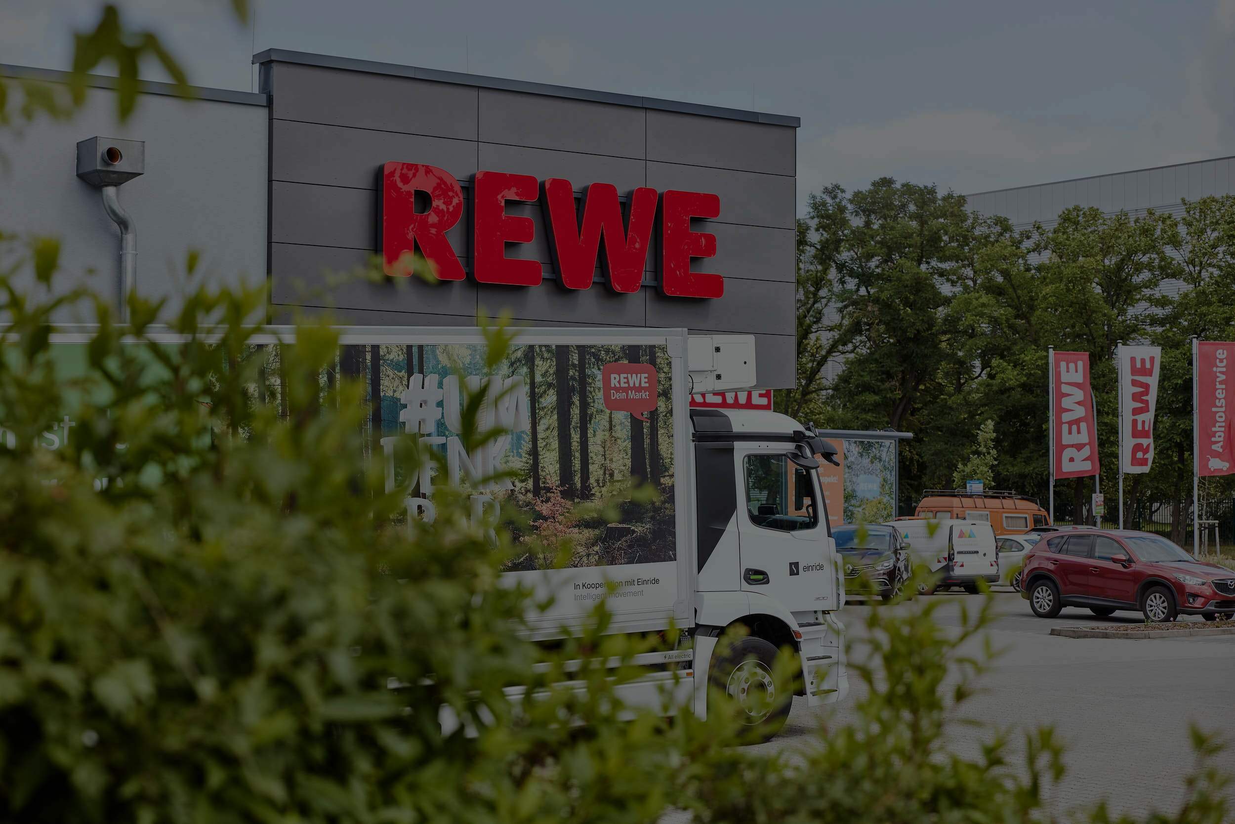 A truck sitting in front of REWE grocery store.