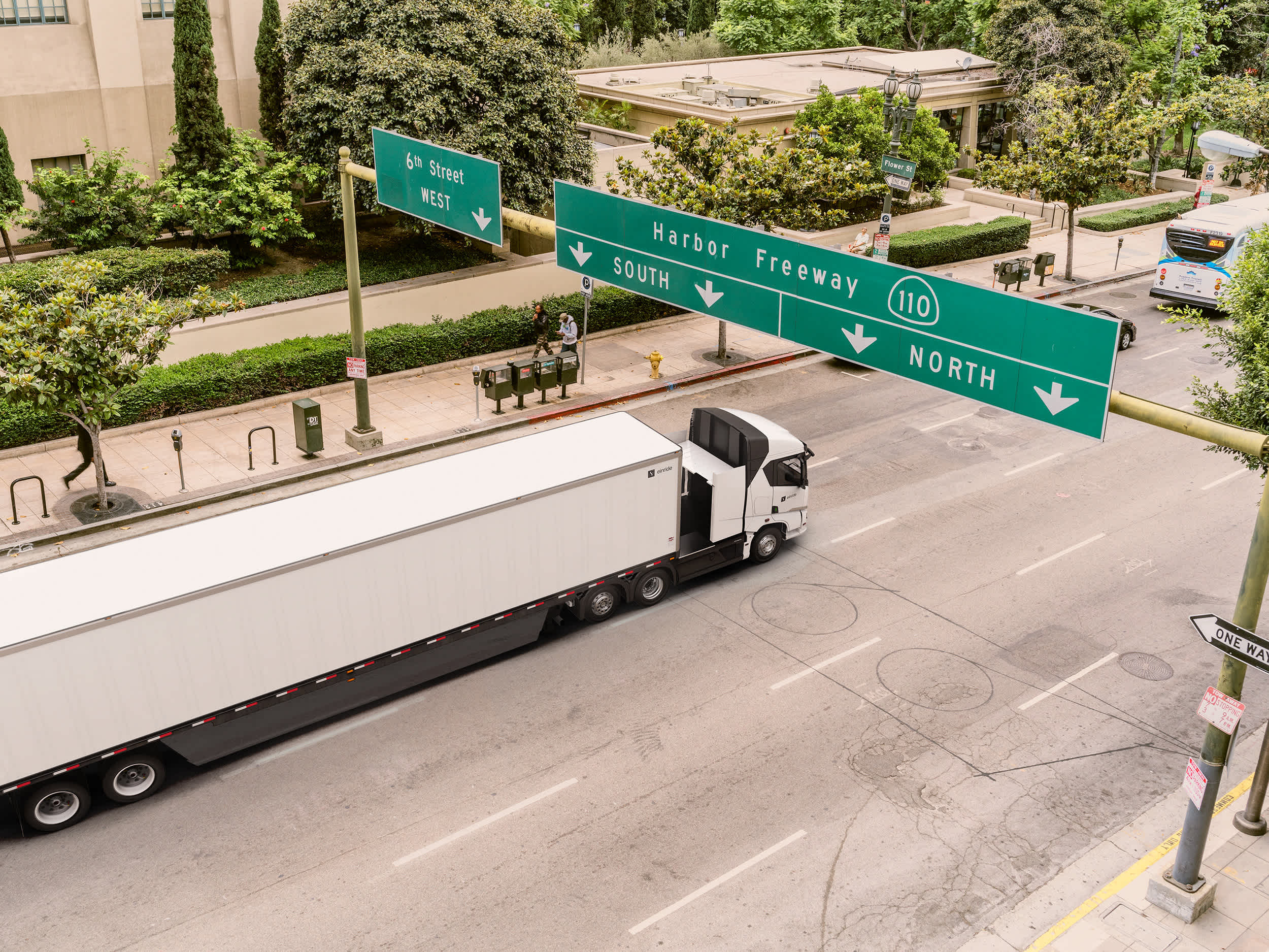 An overhead shot of an electric truck driving through a city during the day,