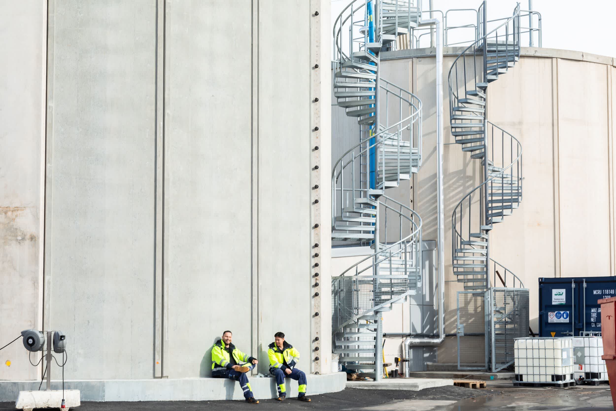 Drivers sitting and talking by a large metal spiral staircase.