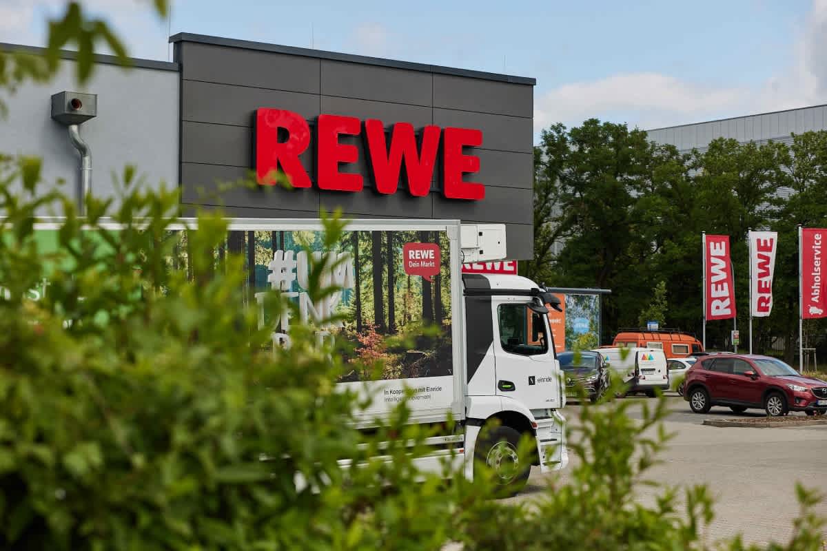 A shot of a REWE grocery store with a truck parked out in front.