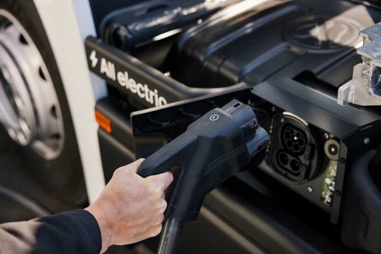 A hand holding a charger and charging an Einride connected electric truck