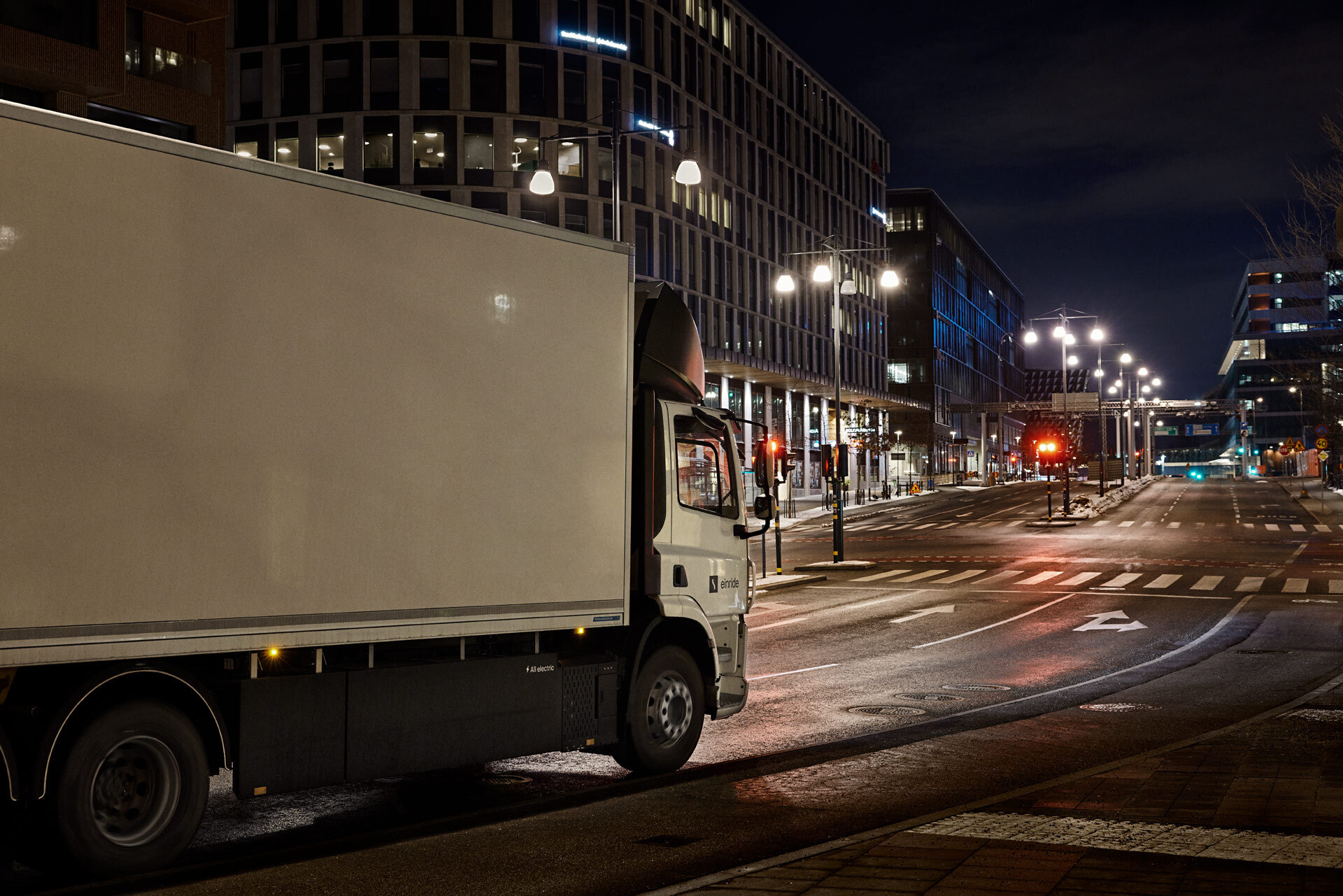 The left side of a truck driving through a city at night.