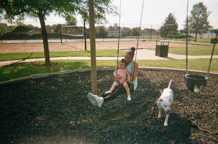 Shabnam at a playground swinging with her daughter and dog
