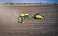 Side view of a tractor planting in an open field