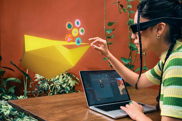 Woman building for the new Spectacles in Lens Studio while viewing the Lens she built and interacting with the Lens features with her hand.