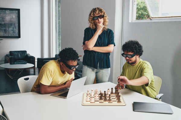 Three people wearing the new Spectacles working on a laptop and playing augmented reality Chess with the new Spectacles.