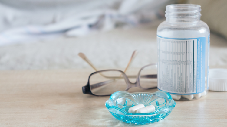 Bottle of pills and reading glasses on table