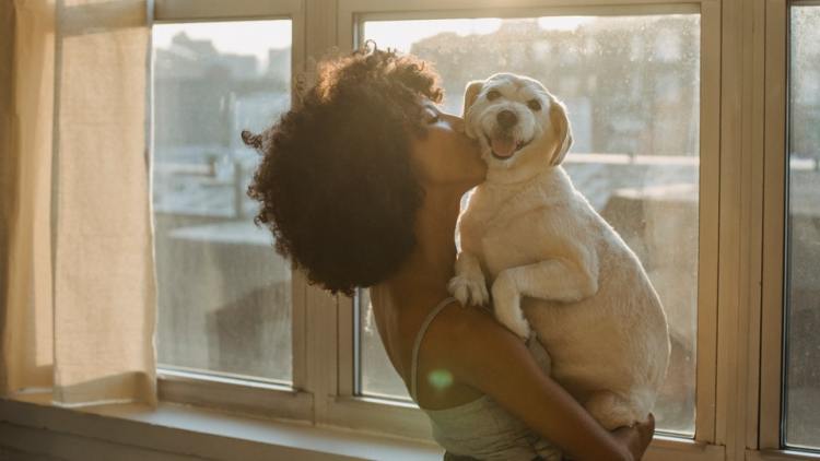 Woman holding dog near window