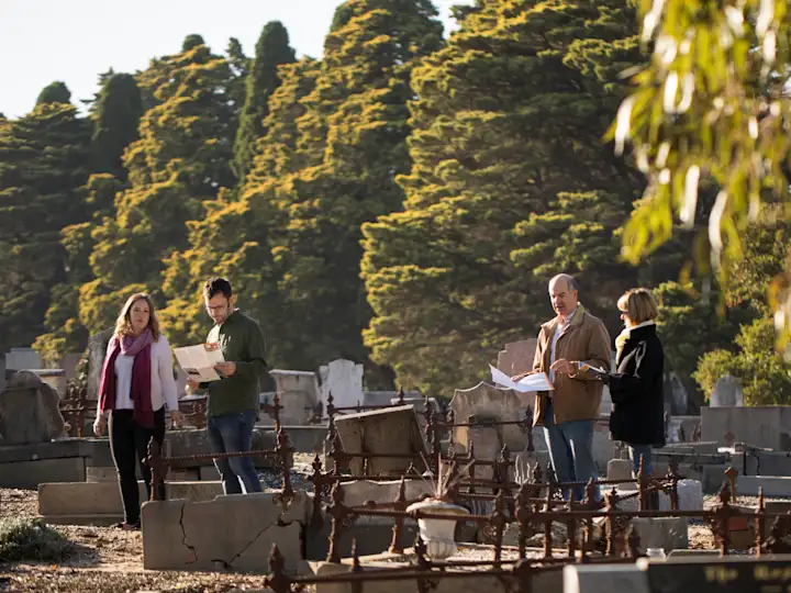 Community members walking through historic Coburg Pine Ridge Cemetery with maps