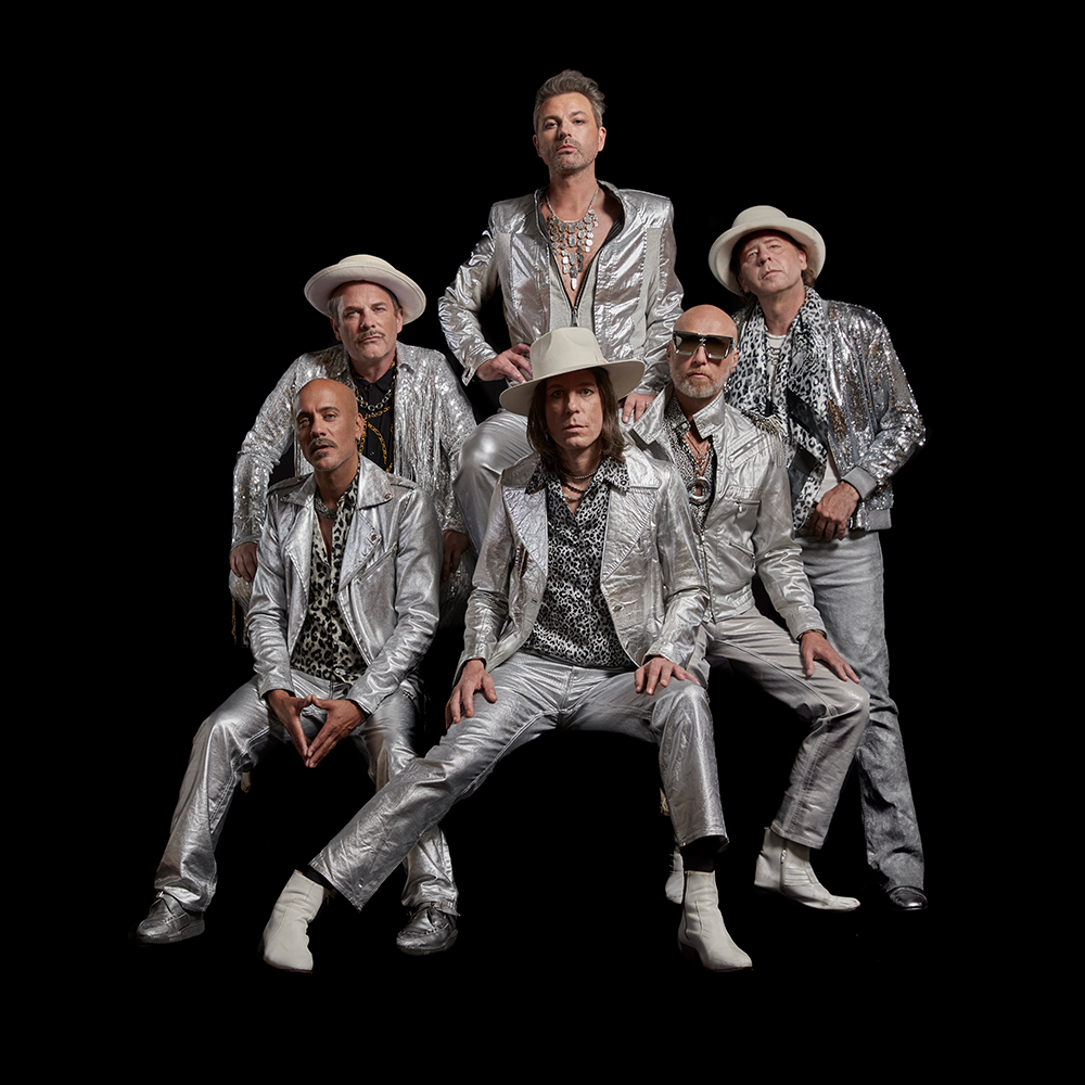 Sex män iförda silverdräkter och hattar poserar tillsammans mot en svart bakgrund.