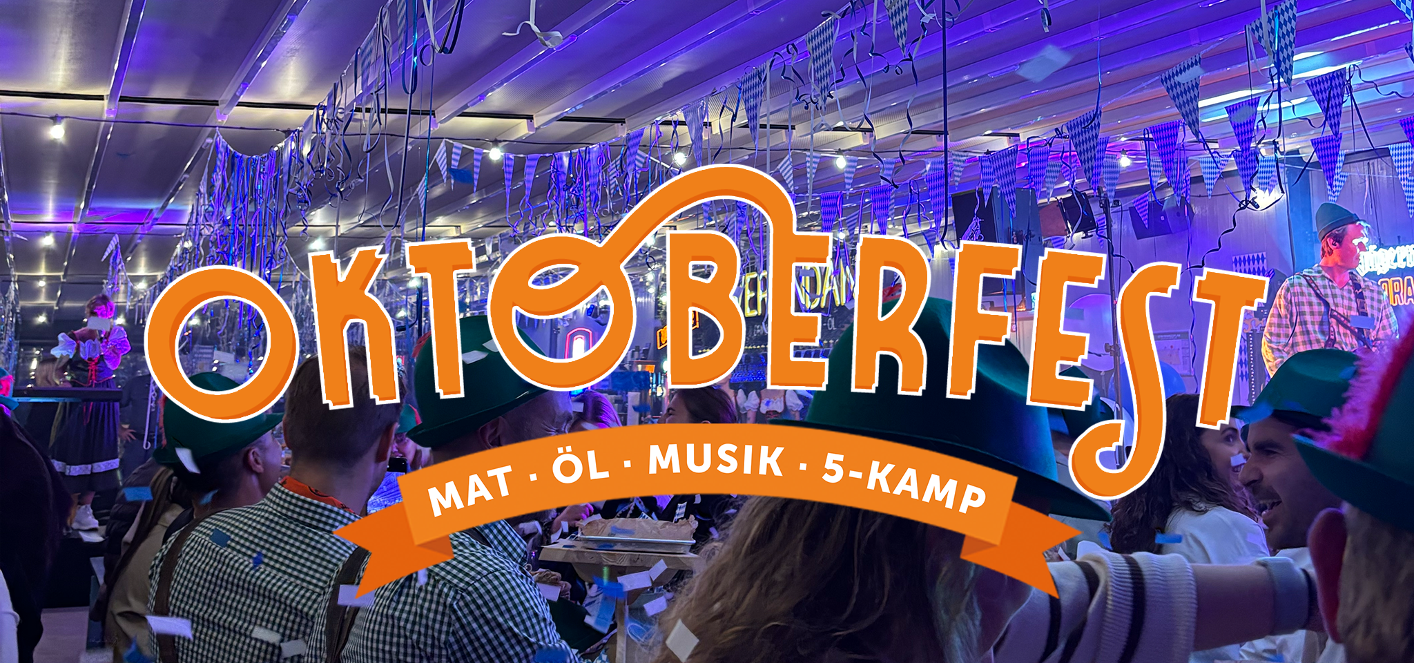People in festive hats attend an indoor Oktoberfest event with decorations, blue lights, and a large banner reading “Oktoberfest – Mat, Öl, Musik, 5-Kamp.”.