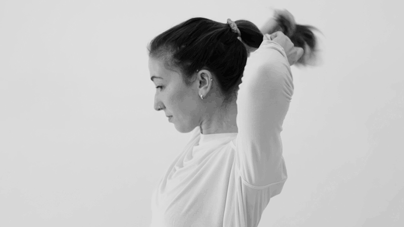 an image of a woman putting her hair into a ponytail with three hair ties  