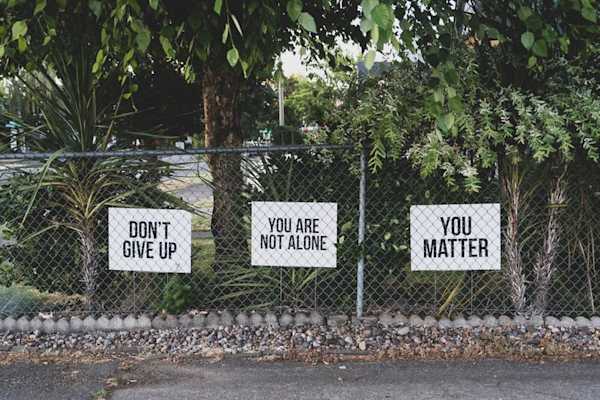 A fence with banners reading: "don't give up", "you are not alone", "you matter".