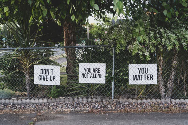 A fence with banners reading: "don't give up", "you are not alone", "you matter".