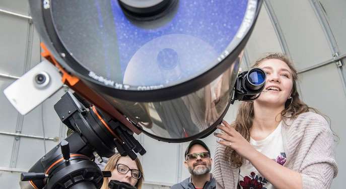 Picture of a student getting to look through a research grade telescope. 