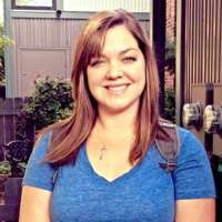 Smiling woman with long brown hair wearing a blue shirt.