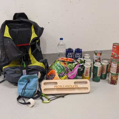 A fingerboard and a backpack with some cans of beers and beans on the floor.