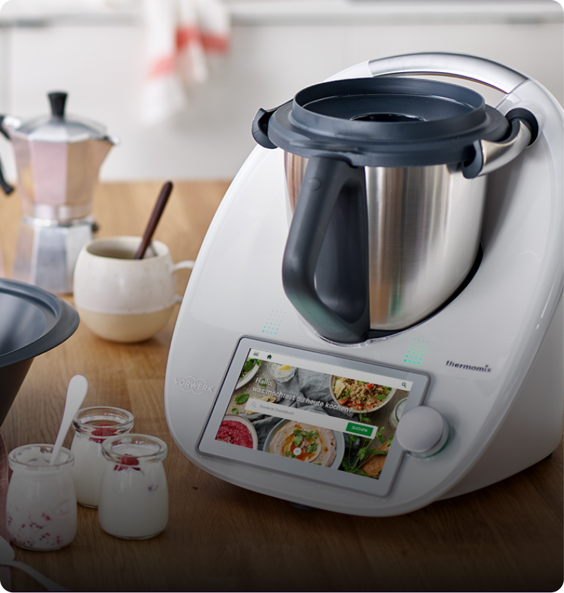 Photo of a Vorwerk Thermomix on a kitchen counter with kitchen supplies next to it