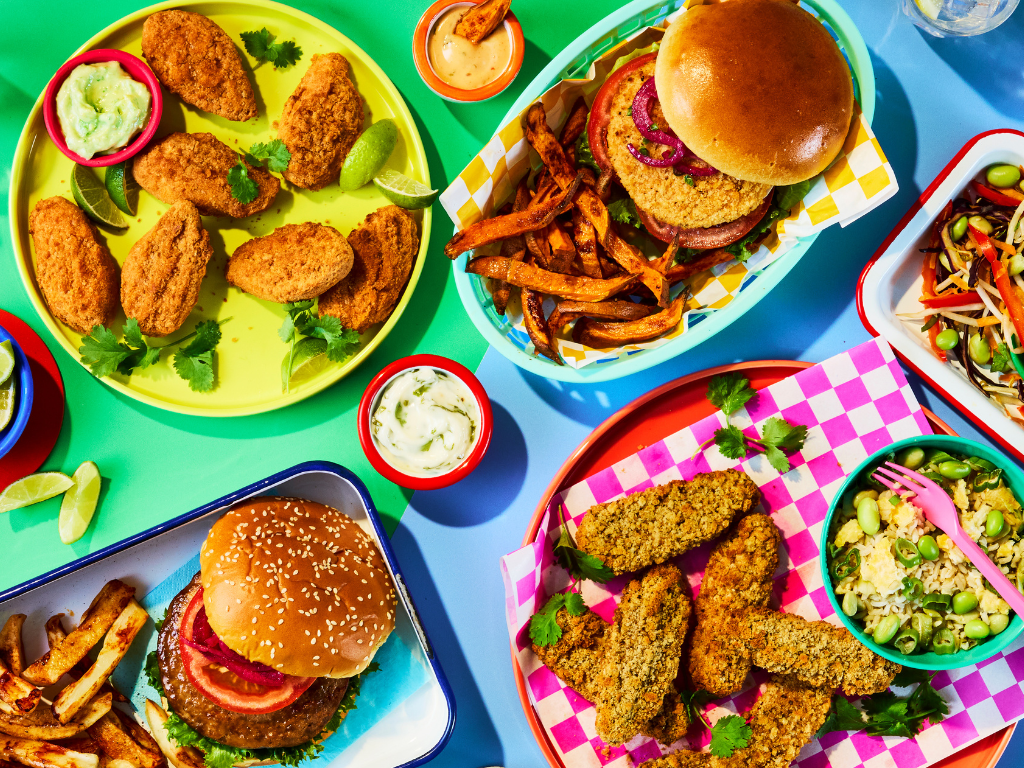 Colourful flat lay spread of Quorn Takeaway vegetarian products, including burgers, crispy tenders, spicy bites, fries, and dipping sauces.