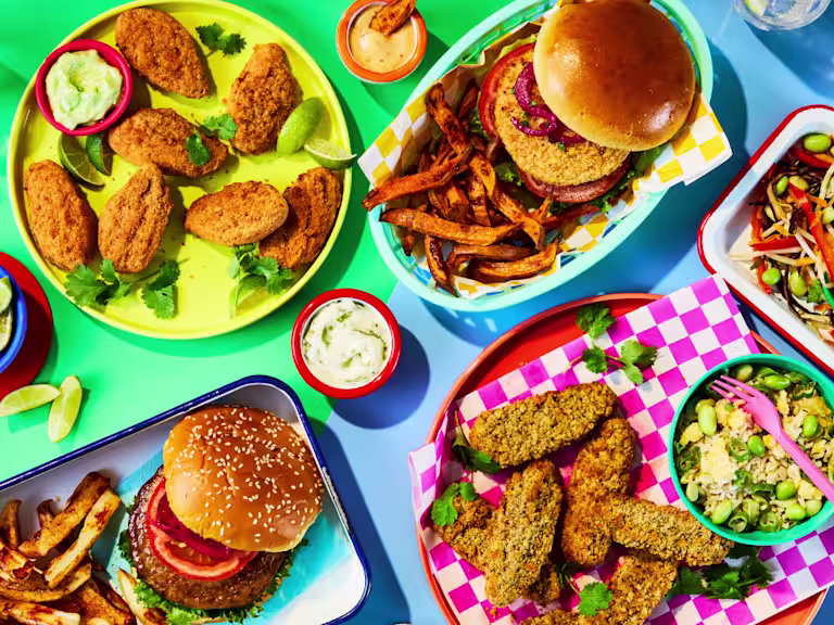 Colourful flat lay spread of Quorn Takeaway vegetarian products, including burgers, crispy tenders, spicy bites, fries, and dipping sauces.