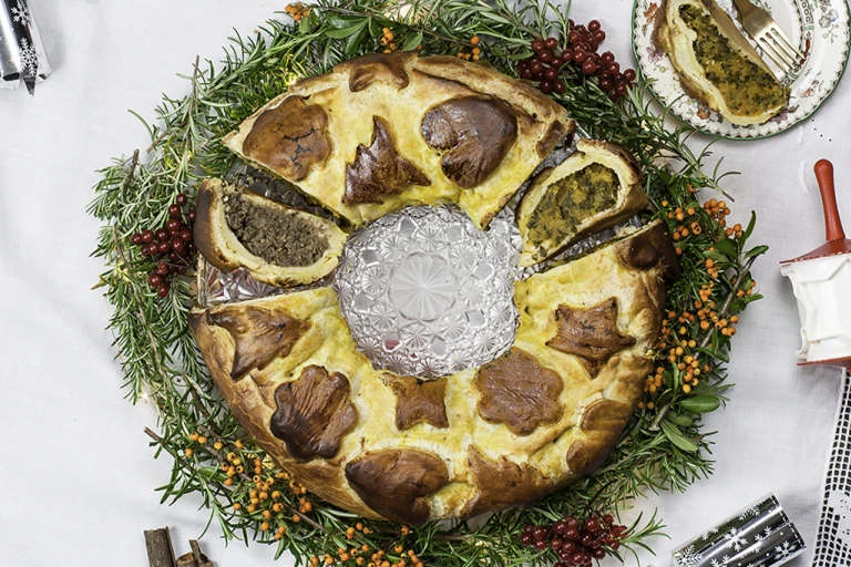 Vegan sausage and butternut squash colcannon wreath, with a piece cut opening facing upwards and a piece on the side. 