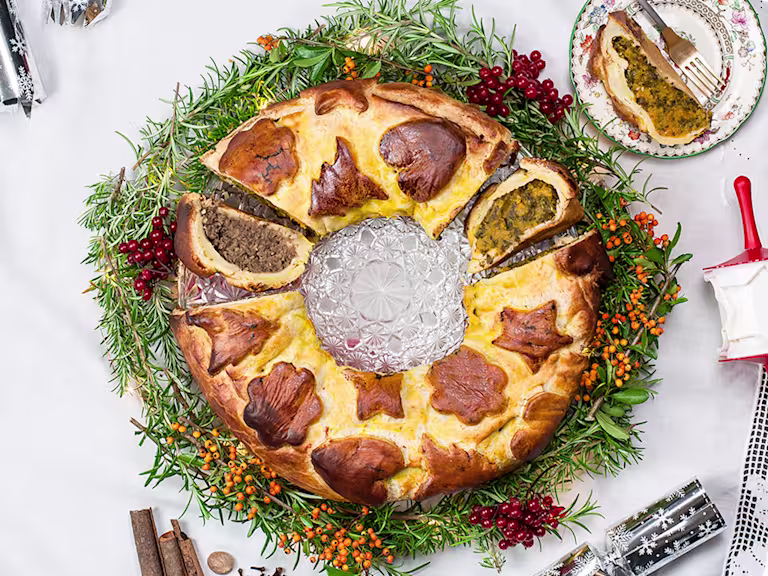 Vegan sausage and butternut squash colcannon wreath, with a piece cut opening facing upwards and a piece on the side.