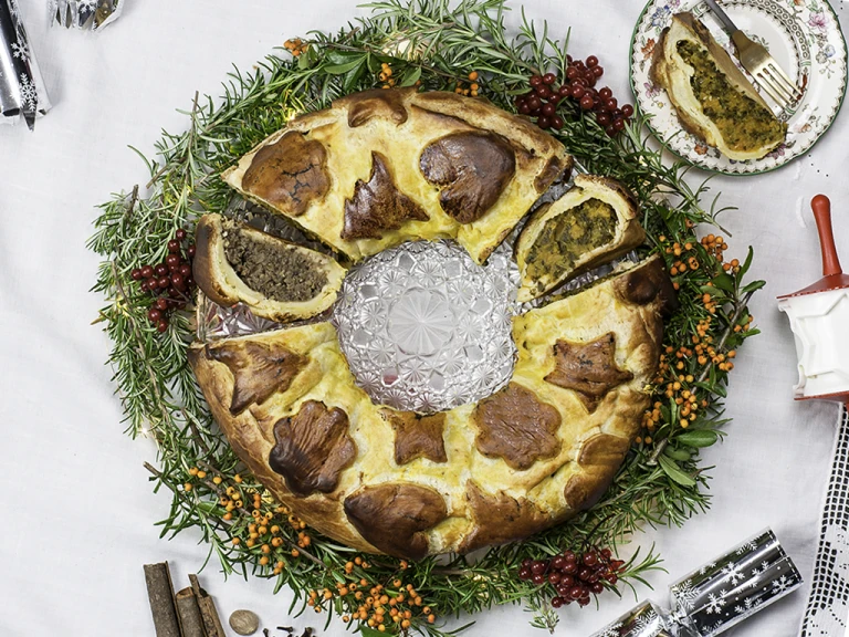 Vegan sausage and butternut squash colcannon wreath, with a piece cut opening facing upwards and a piece on the side. 