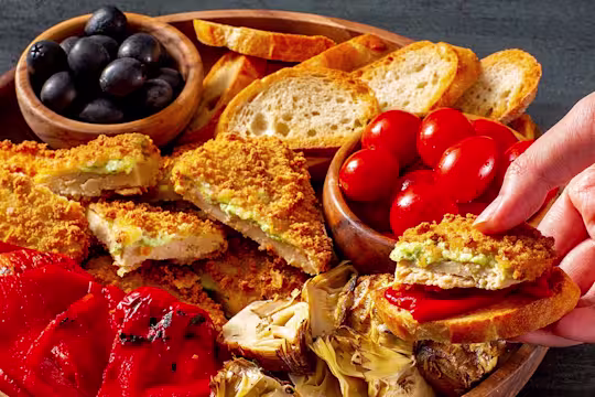 Quorn Meatless Mozzarella and Pesto Cutlets on a platter with tomatoes and olives