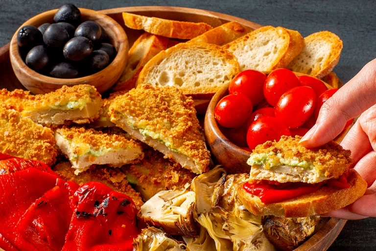 Quorn Meatless Mozzarella and Pesto Cutlets on a platter with tomatoes and olives
