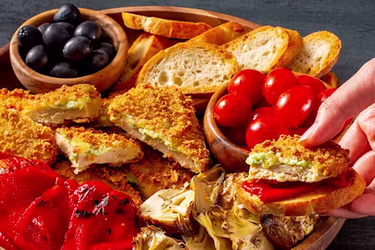 Quorn Mozzarella and Pesto Escalopes on a platter with tomatoes and olives