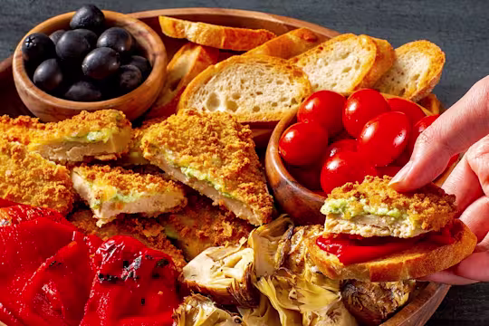 Quorn Mozzarella and Pesto Escalopes on a platter with tomatoes and olives
