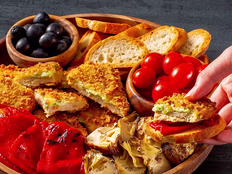 Quorn Mozzarella and Pesto Escalopes on a platter with tomatoes and olives