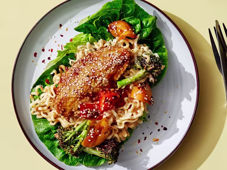 Vegetarisk teriyakigratäng med Quornfiléer serverad på en salladsbädd serverad med en kopp och kniv och gaffel