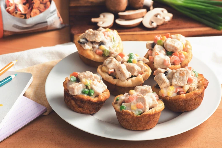 Mini Quorn Piece pot pies with carrots, peas, and corn on a white plate.