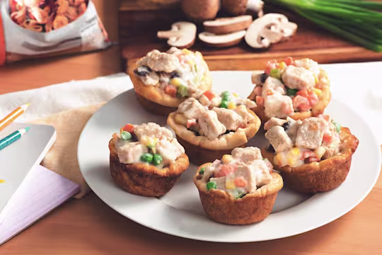 Mini Quorn Piece pot pies with carrots, peas, and corn on a white plate.