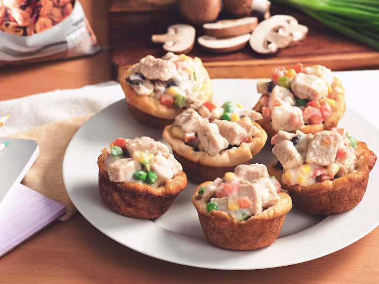 Mini Quorn Piece pot pies with carrots, peas, and corn on a white plate.