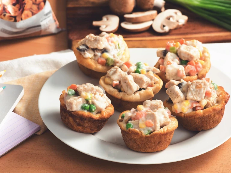 Mini Quorn Piece pot pies with carrots, peas, and corn on a white plate.