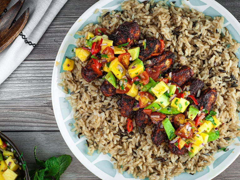 Jerk spiced Quorn fillets with avocado and mango salsa served in a blue bowl.