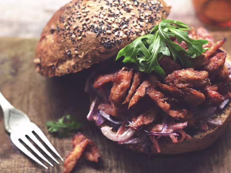 Quorn BBQ Pulled Vegetarian Chicken Fillet served on a wooden board with a fork on the side.