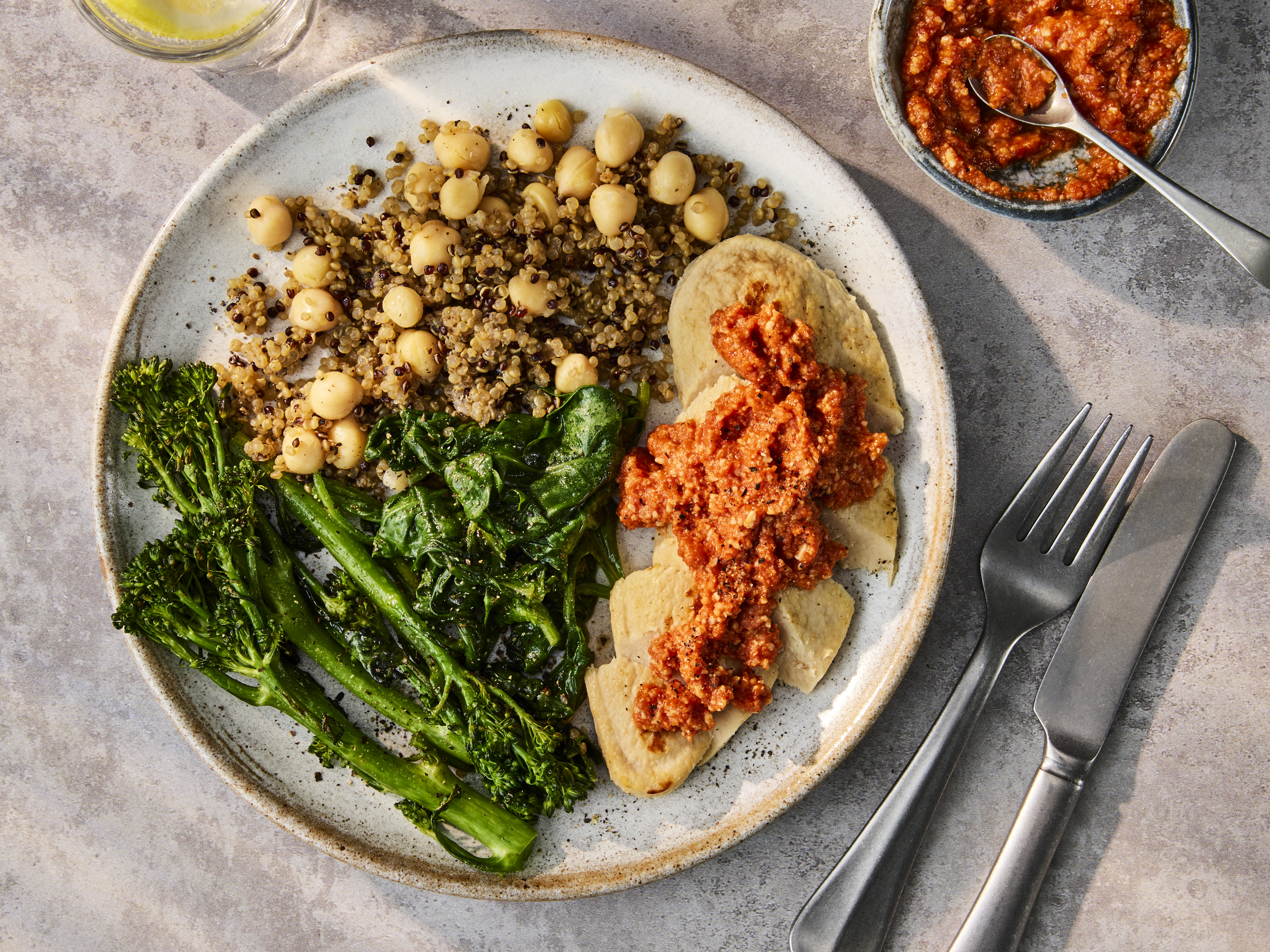 Plated Vegetarian Chicken Fillets with Romesco Sauce, served with a side of quinoa and green vegetables.
