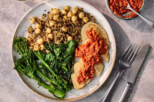 Plated Vegetarian Chicken Fillets with Romesco Sauce, served with a side of quinoa and green vegetables.