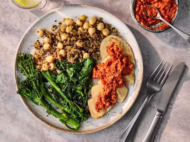 Plated Vegetarian Chicken Fillets with Romesco Sauce, served with a side of quinoa and green vegetables.