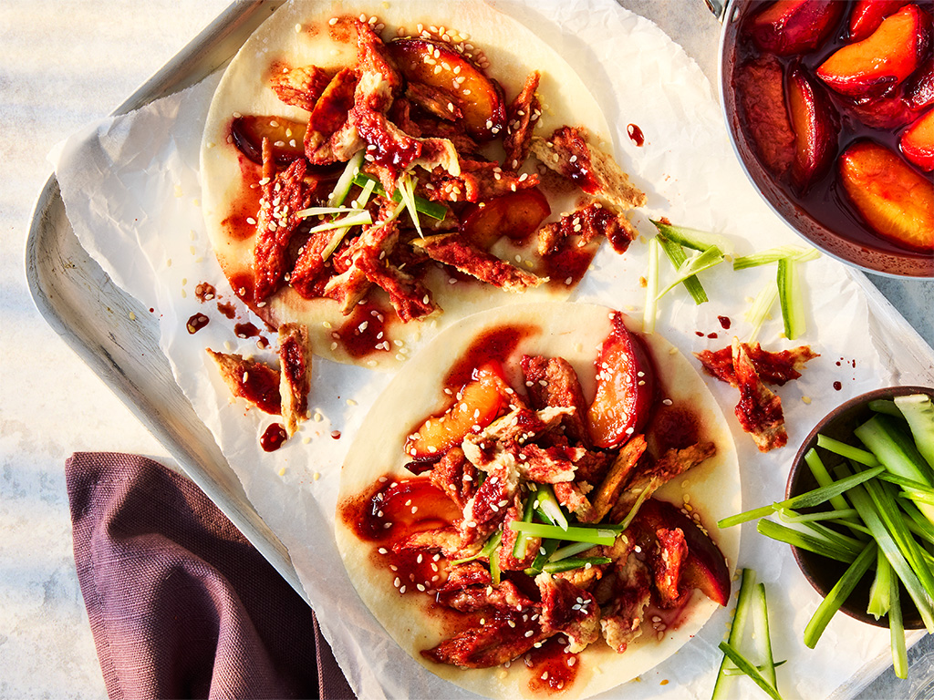 Vegetarian Hoisin Duck Pancakes with Quorn Fillets, cucumber and spring onion on a white plate on a white background.