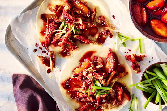 Vegetarian Hoisin Duck Pancakes with Quorn Fillets, cucumber and spring onion on a white plate on a white background.