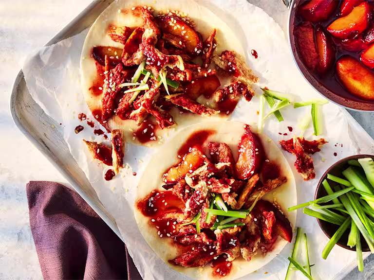 Vegetarian Hoisin Duck Pancakes with Quorn Fillets, cucumber and spring onion on a white plate on a white background.