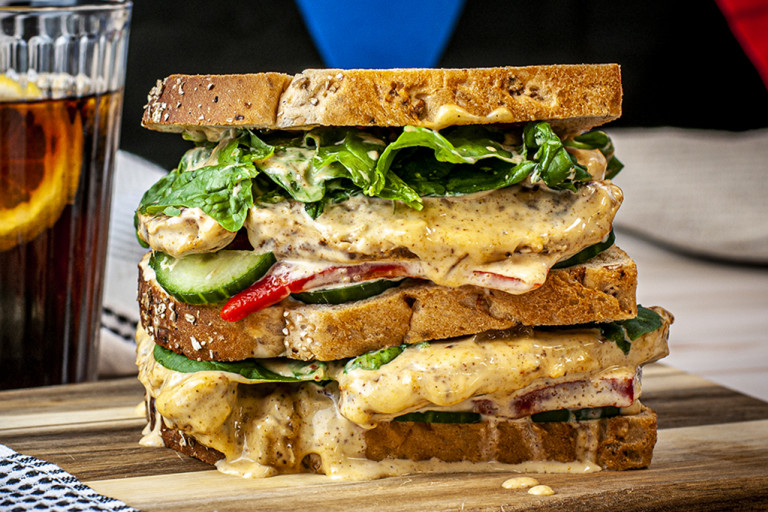 Vegan sandwich served on a wooden board.
